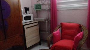 een kamer met een rode stoel en een magnetron bij chez annick et jacques in Vieux Bourg