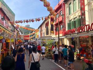 a crowd of people walking down a street with buildings at BEAT Arts Hostel at Chinatown in Singapore