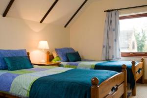 two beds in a room with a window at Windrush Cottage, Seven Springs Cottages in Cheltenham