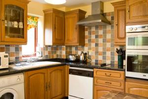 a kitchen with wooden cabinets and a stove top oven at Windrush Cottage, Seven Springs Cottages in Cheltenham