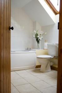 a bathroom with a toilet and a tub and a sink at Windrush Cottage, Seven Springs Cottages in Cheltenham