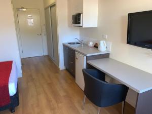 a small kitchen with a desk and a room with a bed at Weipa Motel Resort in Weipa