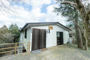 uma pequena casa branca com um grande deque de madeira em Chojuyu Hakone em Hakone