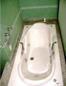 a bath tub in a bathroom with a green wall at Hotel Rosa Mar in Macaé