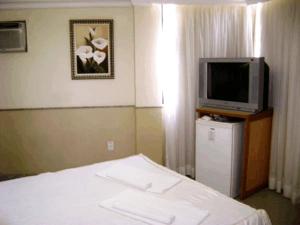 um quarto de hotel com uma cama e uma televisão em Hotel Rosa Mar em Macaé