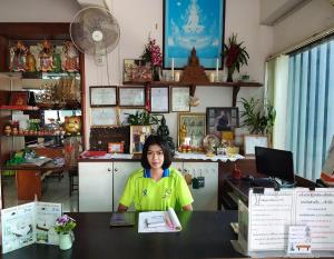 una mujer sentada en una mesa en una habitación en อาร์.เจ.แมนชั่น, en Chonburi