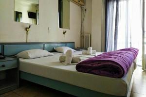 sypialnia z dużym łóżkiem i fioletowym kocem w obiekcie Delfini Hotel w Pireusie