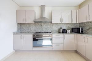 a white kitchen with white cabinets and a stove at Frank Porter - Mon Reve in Dubai