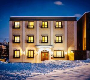 札幌Miidokoro House Hotel的一座大建筑,在雪中灯火通明