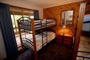 a bedroom with two bunk beds and a mirror at Ellimata Holiday Cottage in Halls Gap