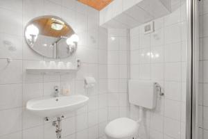 a white bathroom with a sink and a toilet at Ferienwohnung König im Erdgeschoss in Berchtesgaden +7 photos