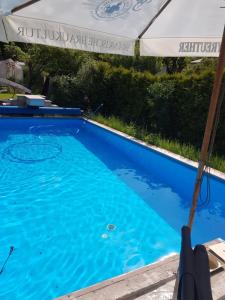 a pool with an umbrella and a swimming pool at kleine Ferienwohnung Schortestraße in Ilmenau