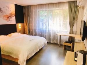 een slaapkamer met een bed, een bureau en een raam bij  Shenzhen Hualian Boutique Hotel in Shenzhen