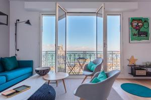 d'un salon avec un canapé bleu et d'un balcon. dans l'établissement ALTAYA Apt with balcony and sea view in Biarritz, à Biarritz