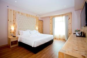 a bedroom with a large white bed and a window at Vouk Hotel Suites, Penang in George Town