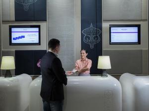 
a man and woman are looking at a television screen at Mercure Pattaya Ocean Resort - SHA Extra Plus in Pattaya
