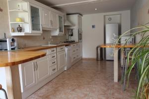 a kitchen with white cabinets and a tile floor at La ferme de Fumichon in Tour-en-Bessin