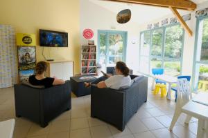two women sitting in chairs in a living room at Camping Le Hameau du Petit Lay in Mouchamps