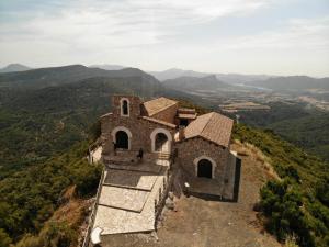 un antiguo edificio en una colina con montañas en el fondo en Casa Nasiet, en Camporrells