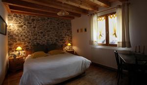 a bedroom with a bed and a desk and a window at La Roche Meane in Villar-dʼArène