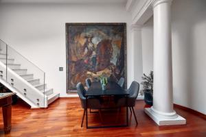 a dining room with a table and a painting on the wall at L' Hôtellerie Easy Suites in Palermo