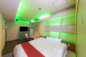 和歌山市にあるホテル　ティーオーのベッドルーム(大きな白いベッド1台、緑の照明付)