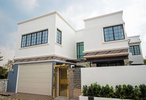 a white house with a garage at Pool Villa Pattaya 5BD - Exquisite Pool Villa G in Nong Prue
