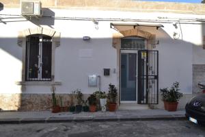 a white house with a door and plants on the sidewalk at Regina Lucia casa vacanze in Siracusa