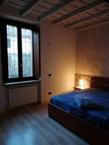 a bedroom with a bed with a blue comforter and two windows at Appartamento in storica Cascina Lombarda Cusago Rho-Fiera-San-Siro in Cusago