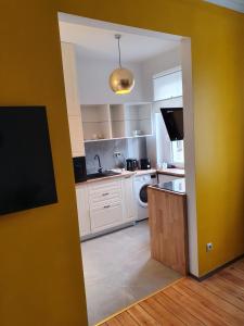 a kitchen with white appliances and a yellow wall at B&B MILES APARTMENT in Katowice