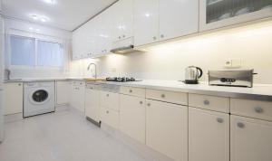 cocina con armarios blancos, lavadora y secadora en Apartment Castell, TarracoHomes, en Salou