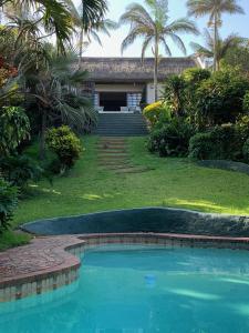 a house with a swimming pool in front of a yard at Thatch by the Sea in Blythedale