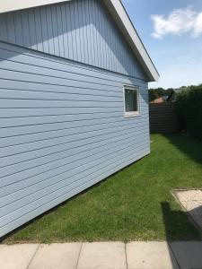 a white garage with a grass yard next to a house at Burgvliet 33 in Oostkapelle