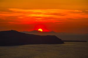 einen Sonnenuntergang über dem Meer mit der Sonne am Himmel in der Unterkunft The Last Sunbeam - Adults Only in Fira