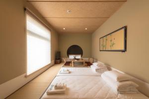 ein Schlafzimmer mit zwei Betten mit weißen Kissen in der Unterkunft 谷町君Hotel 松竹雲 京都四条烏丸 in Kyoto