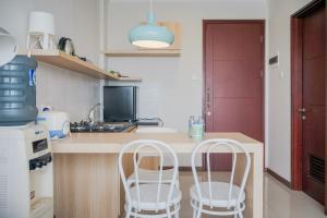 a kitchen with two white chairs and a counter at Cozy 1BR Asatti Apartment By Travelio in Tangerang