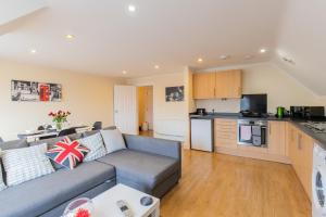 uma sala de estar com um sofá e uma cozinha em 2 Bedroom Penthouse, Clockhouse, Hoddessdon em Hoddesdon
