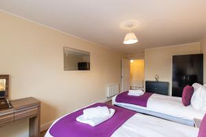 2 letti in una camera con coperte viola di 2 Bedroom Penthouse, Clockhouse, Hoddessdon a Hoddesdon