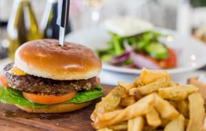 a hamburger and french fries on a wooden table at Island Boutique Hotel in Larnaca