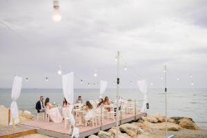 a wedding party sitting on a dock on the beach at Island Boutique Hotel in Larnaca