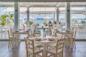 a restaurant with tables and chairs with the ocean in the background at Island Boutique Hotel in Larnaca