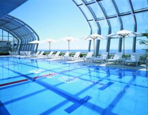 una piscina con sillas y sombrillas blancas en The Gran Resort Elegante Awajishima, en Awaji