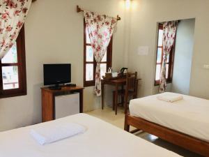 a bedroom with two beds and a television and windows at Pai Flora Resort in Pai