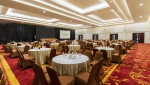 a conference room with tables and chairs and a screen at Ascent Premiere Hotel and Convention in Malang