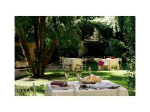 een tafel met wijnglazen en een standbeeld in een tuin bij Hotel Quirinale in Rome
