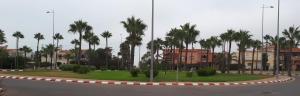 a roundabout with palm trees and buildings in a city at Riad Sidi Rahal Beach in Sidi Rahal