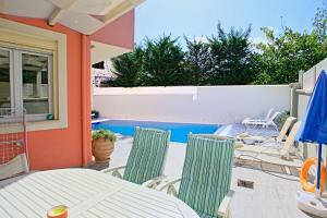 a patio with a table and chairs and a pool at The Doctors House in Kassiopi