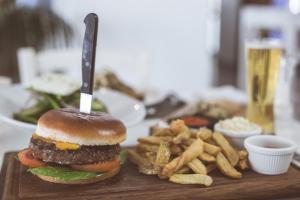 a hamburger and french fries on a cutting board with a knife at Island Boutique Hotel in Larnaca