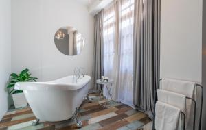 een badkamer met een wit bad en een raam bij Redrum Tbilisi Boutique Hotel in Tbilisi City
