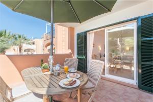 una mesa de madera y sillas en un patio con sombrilla en Burgit, en Portopetro